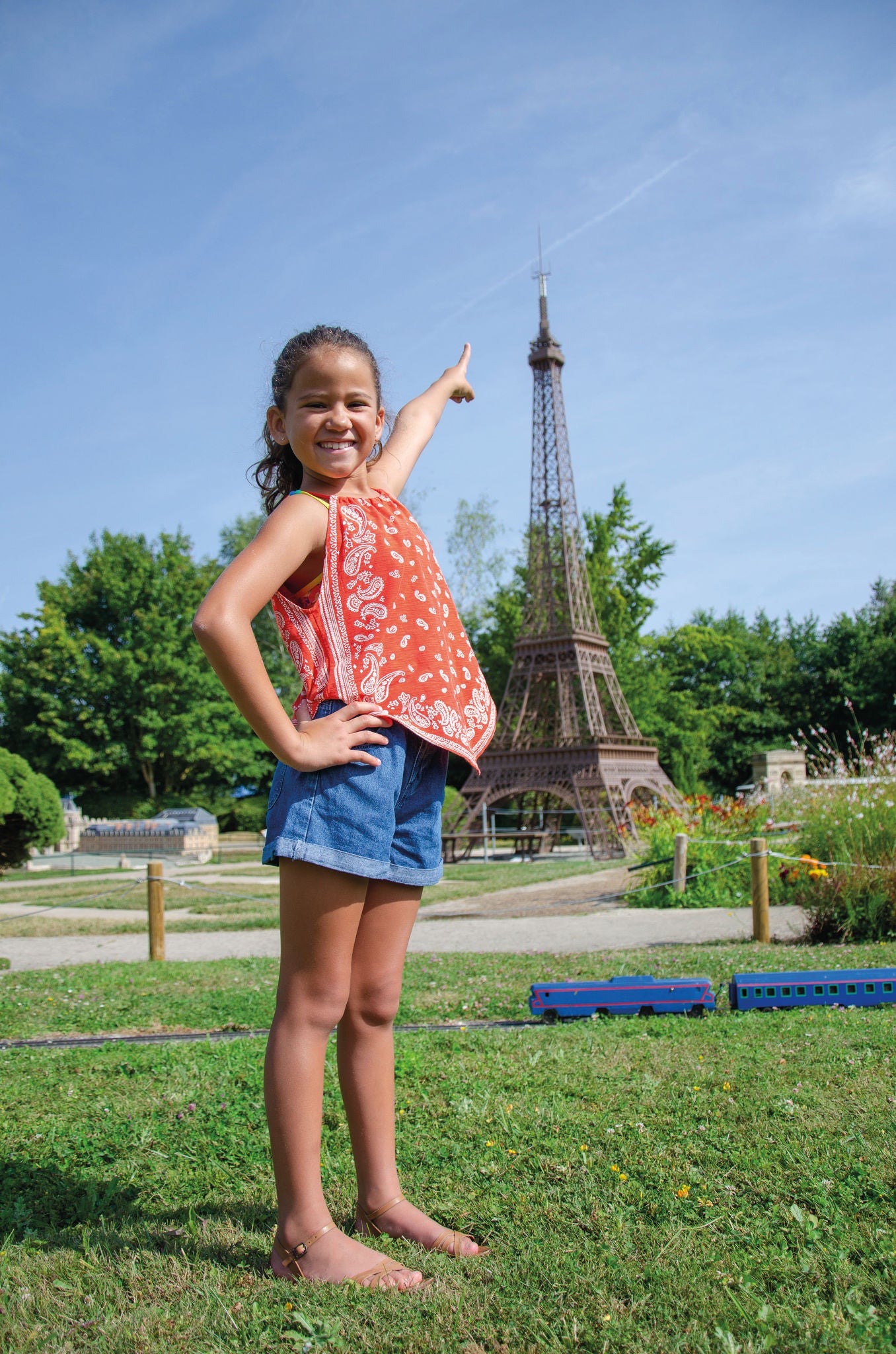 Picture of a girl pointing her finger at the miniature Eiffel tower at France Miniature